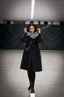 Side profile of a model in an awoke black jacket walking through a minimalist gallery space.