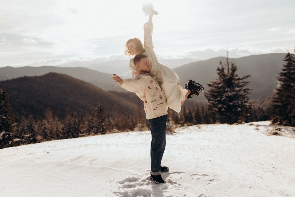 a man holding a little girl on top of a snow covered slope