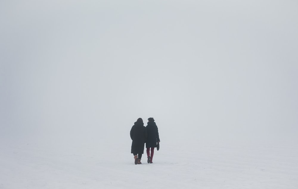 two people standing in the middle of a snow covered field