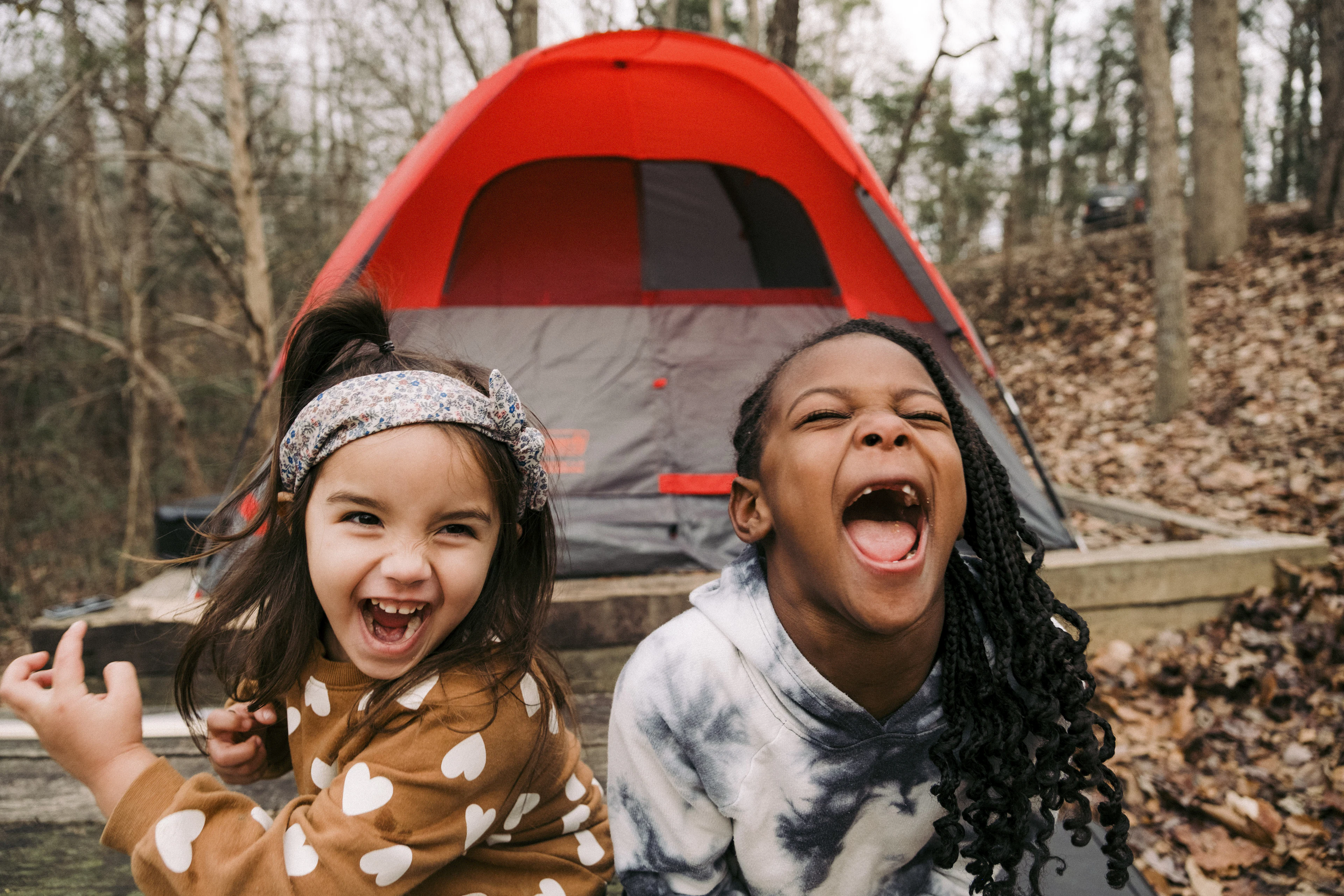 Two laughing girls in front of a red dome tent