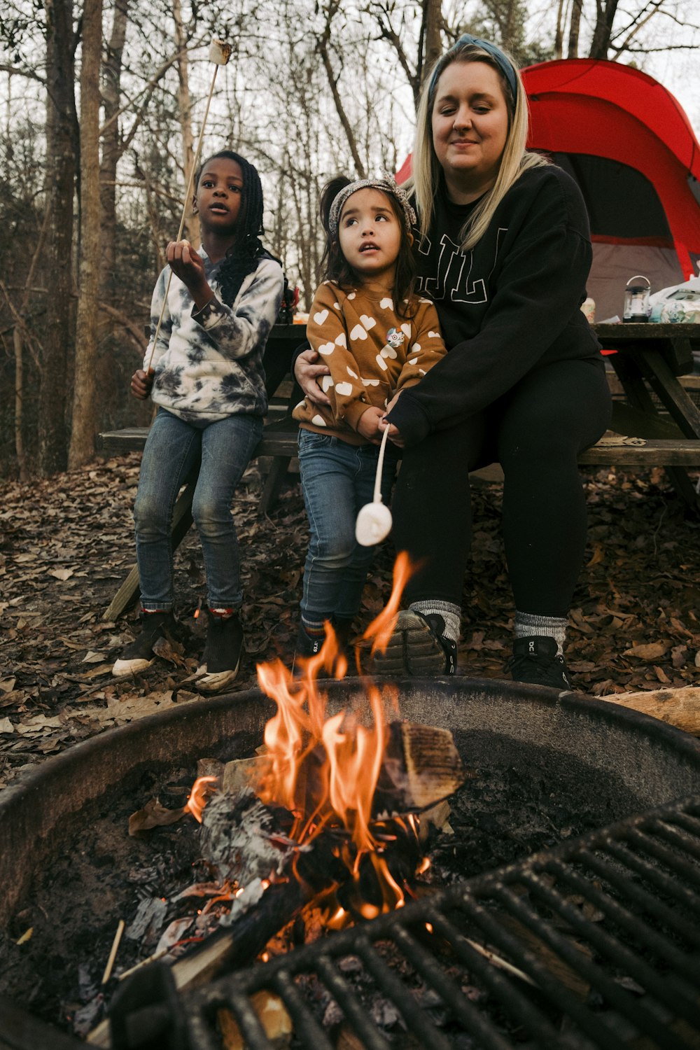 a woman and two children cooking on a grill