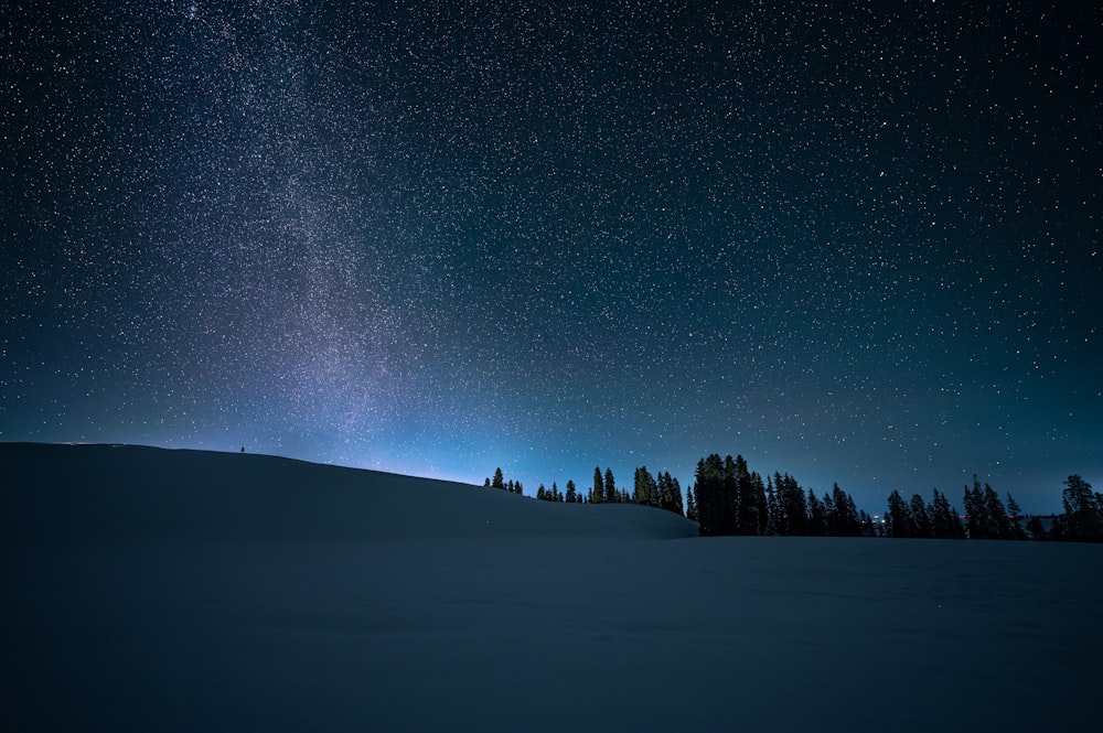 the night sky with stars above a snow covered field