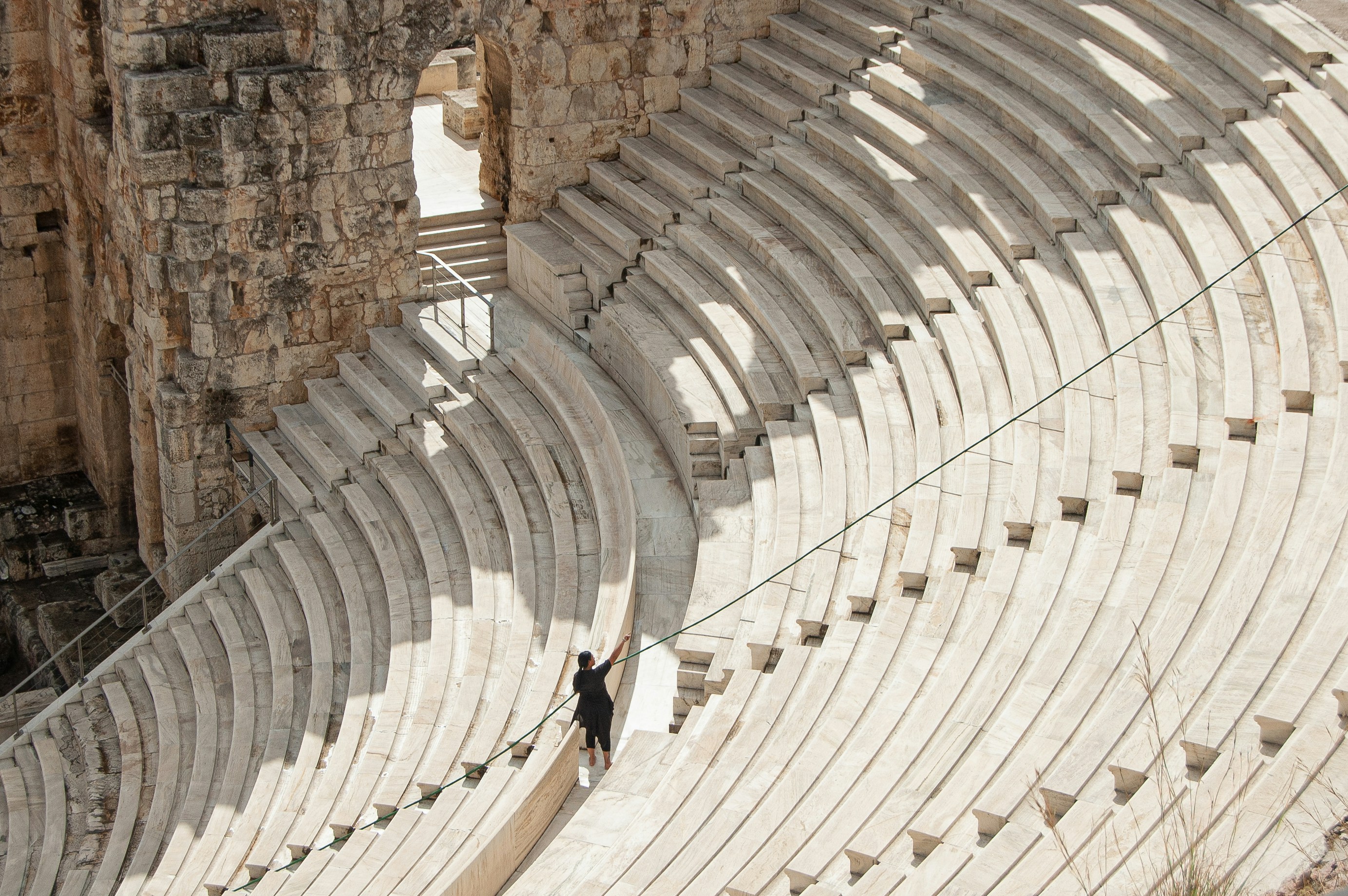 um homem de pé em uma corda na frente de uma ampola de pedra
