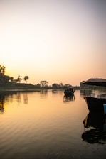 A peaceful river scene at dawn with boats gently floating on the water.