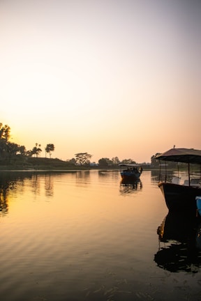 Sunrise over the Ganges river, with boats gently floating near the shore.