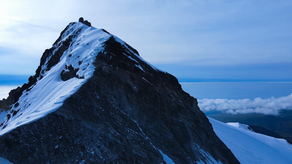 a mountain peak covered in snow and clouds