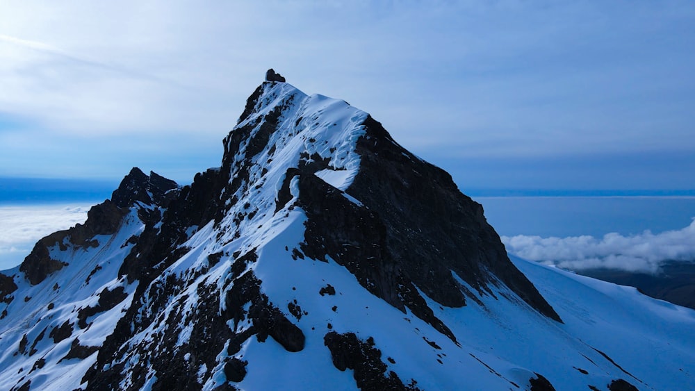 a snow covered mountain peak with clouds in the background