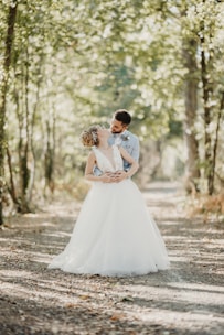 A loving couple dressed as bride and groom standing close together in a flower-filled forest.