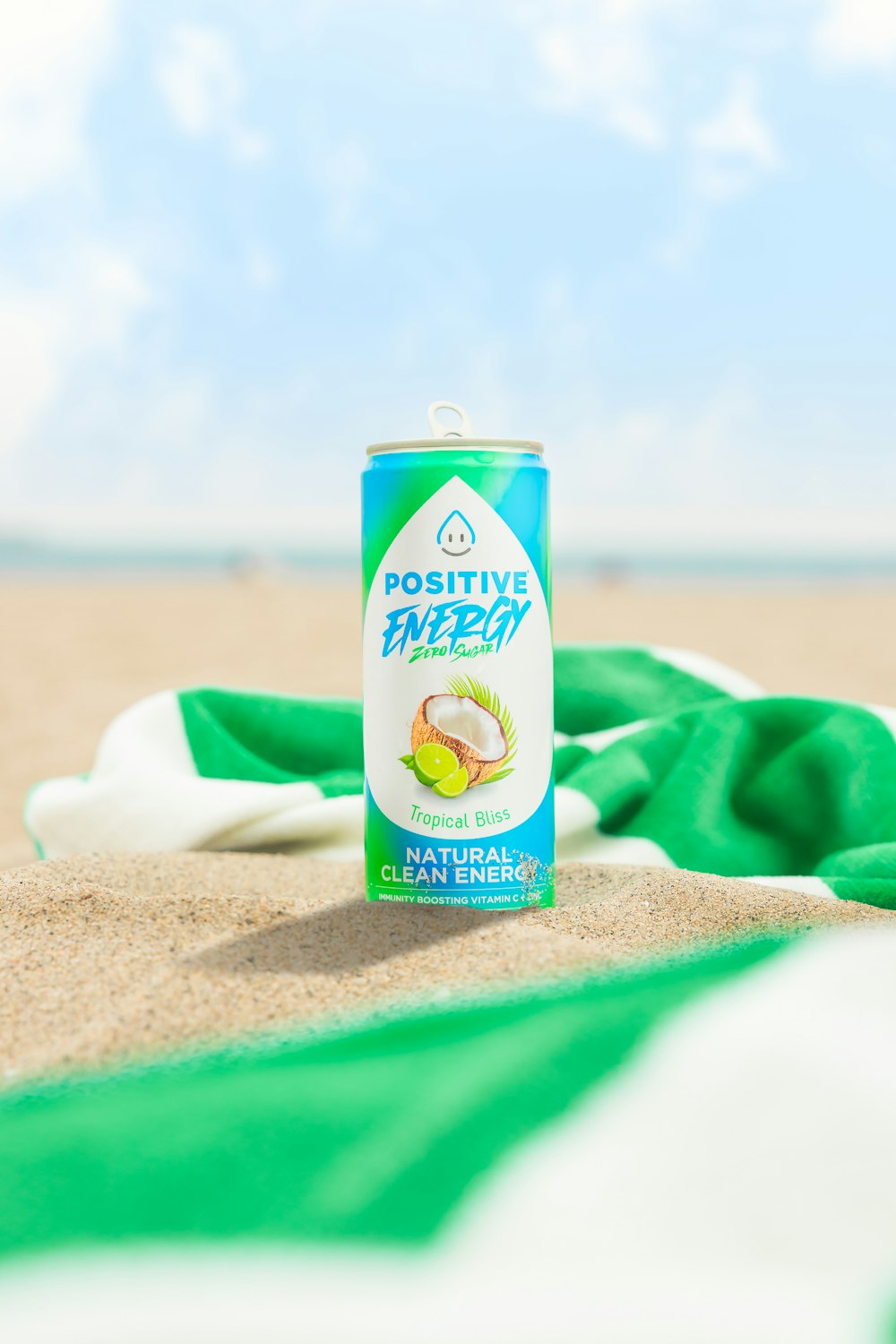a can of drink sitting on a towel on the beach
