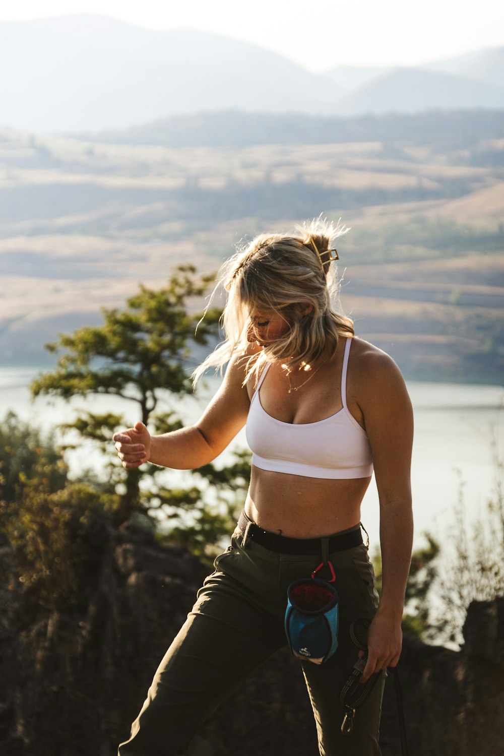 a woman in a sports bra top standing on top of a mountain