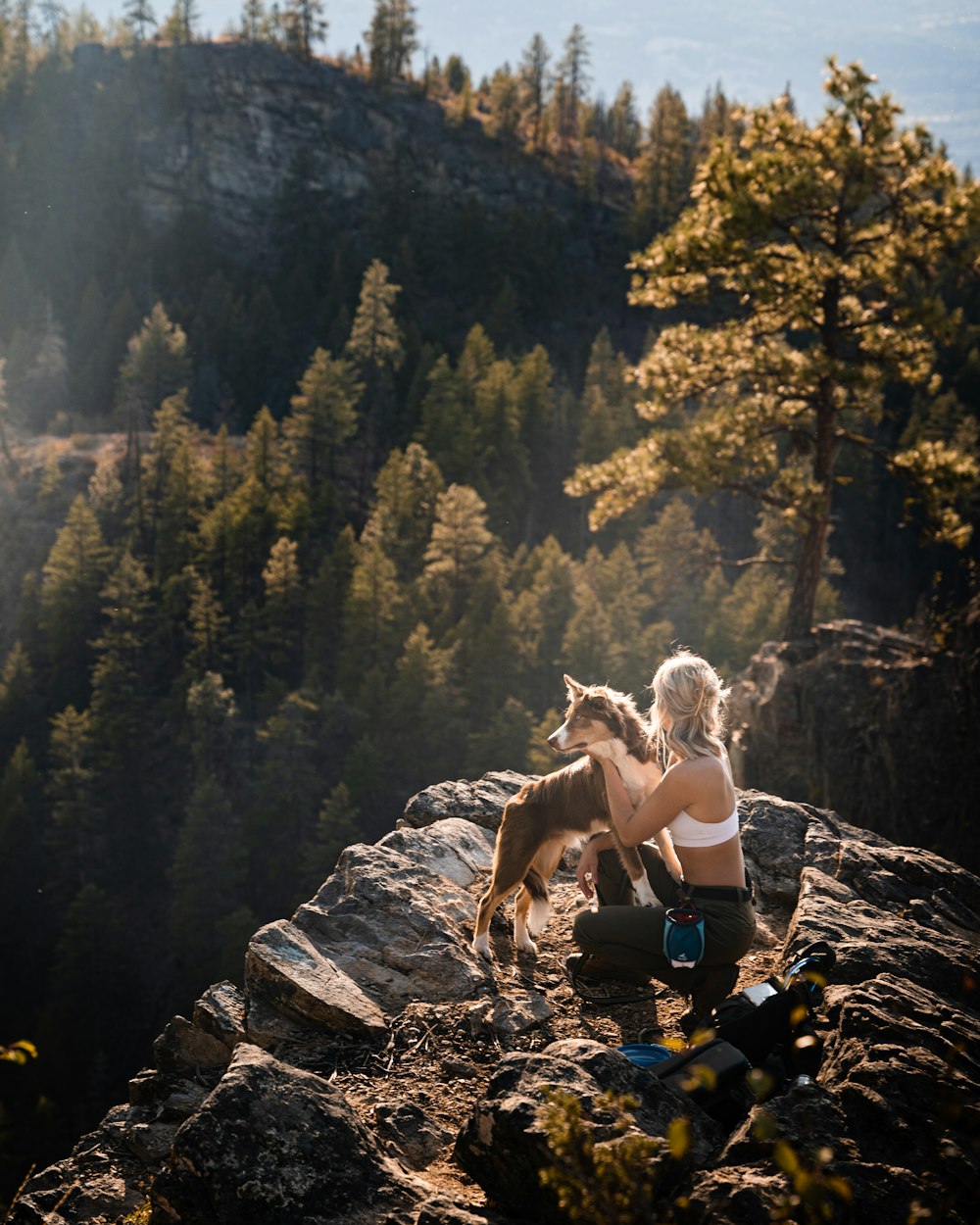 a woman sitting on a rock with a dog