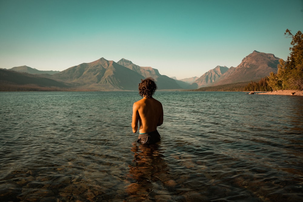 a person standing in a body of water with mountains in the background