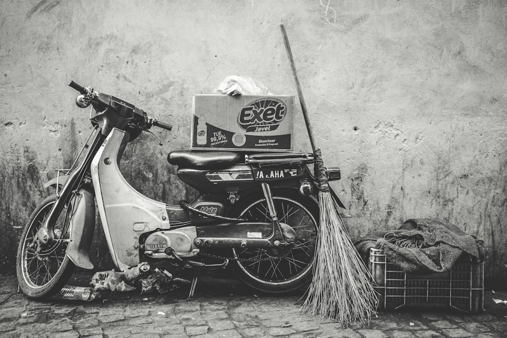a moped parked next to a wall with a box on the back of it