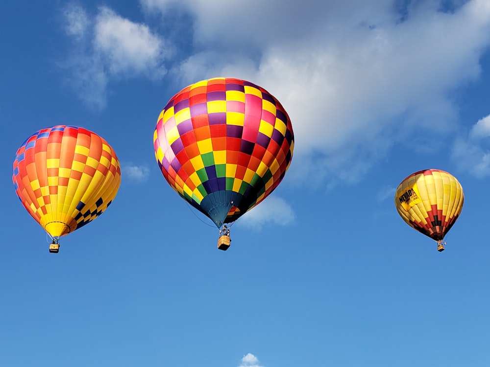 a group of hot air balloons flying through a blue sky