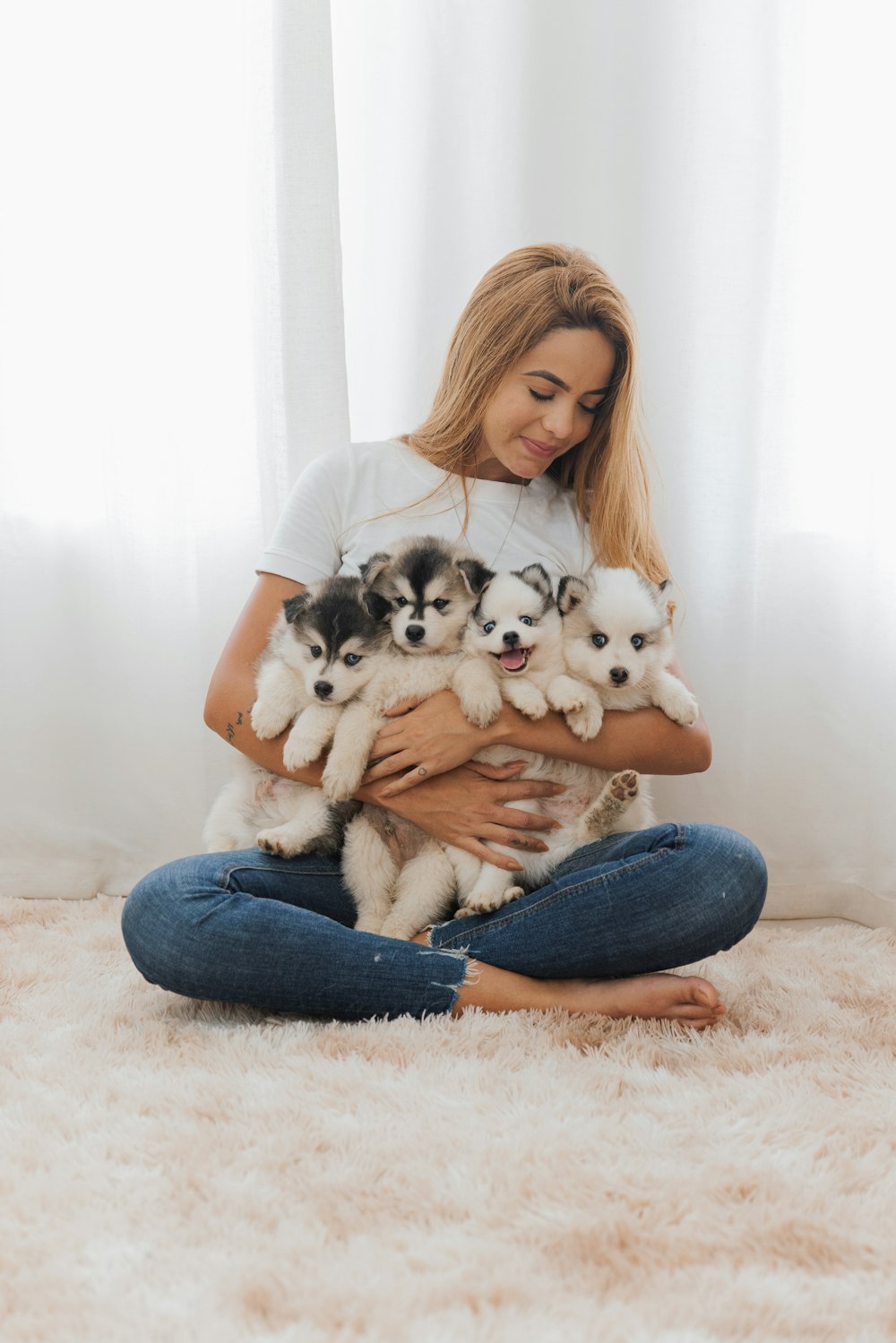 a woman sitting on the floor holding a bunch of puppies