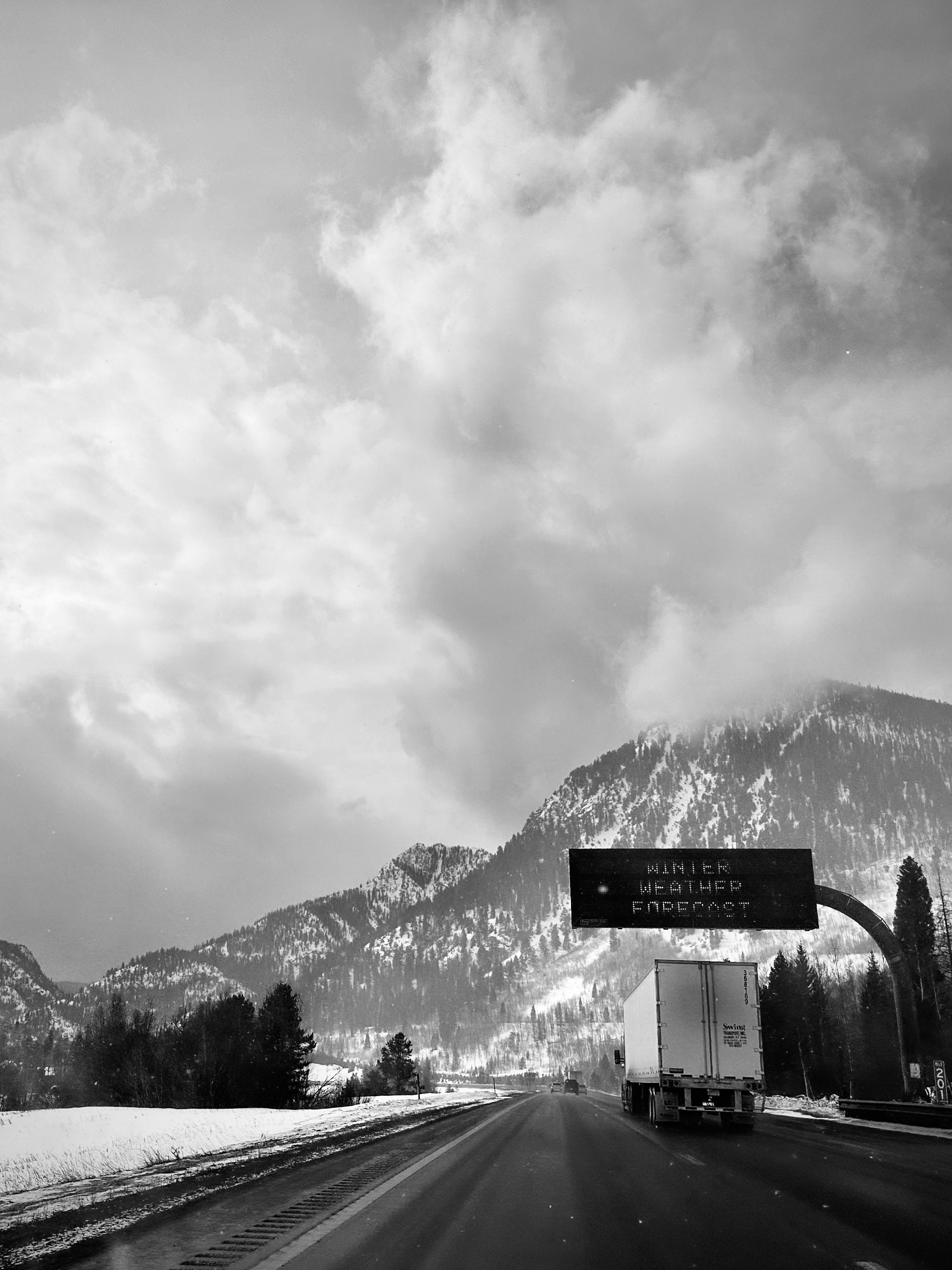 Ein Schwarz-Weiß-Foto einer Autobahn mit Bergen im Hintergrund