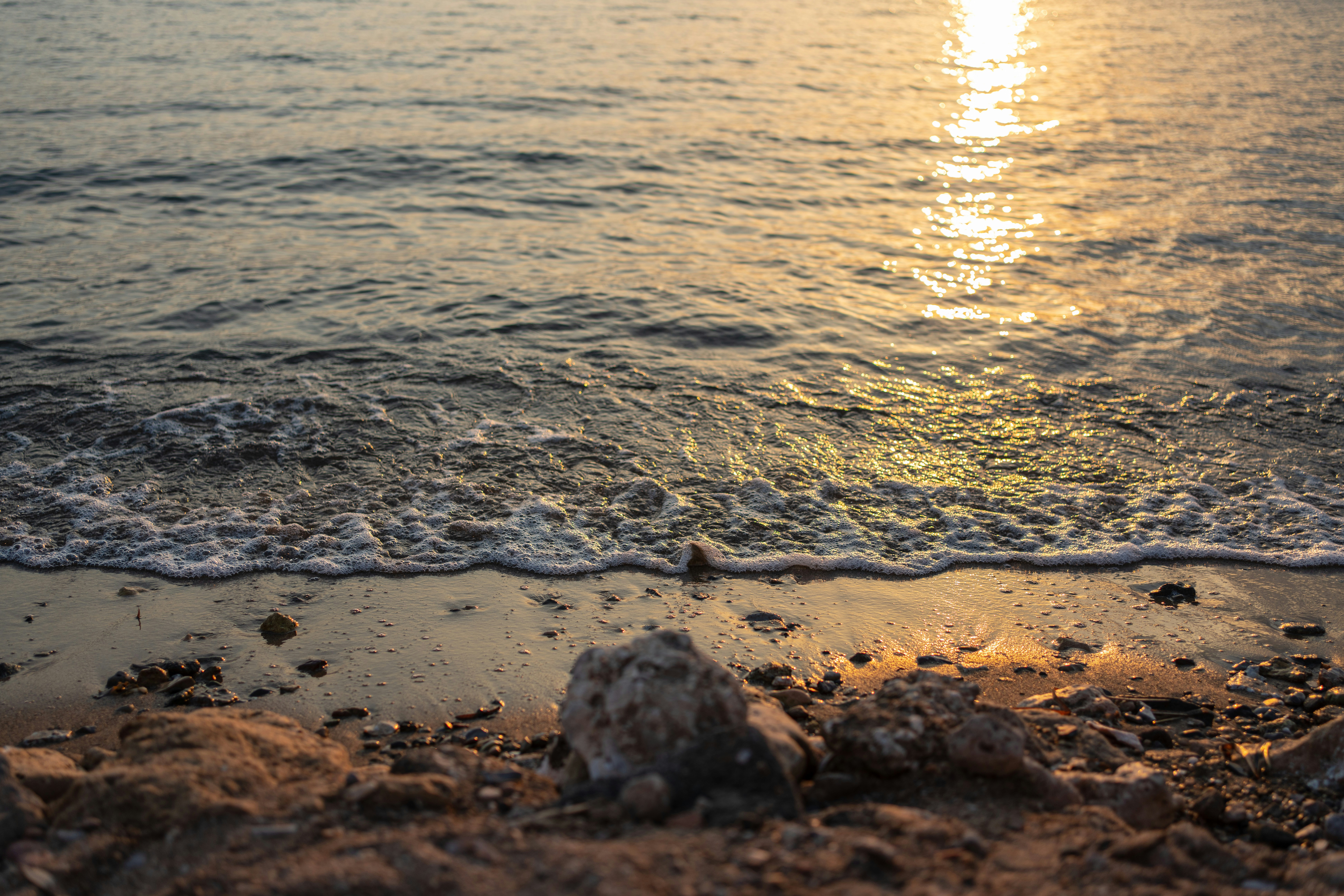 the sun is setting over the water at the beach