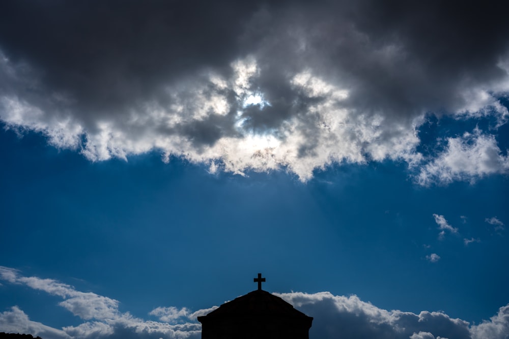 une croix au sommet d’un bâtiment sous un ciel nuageux