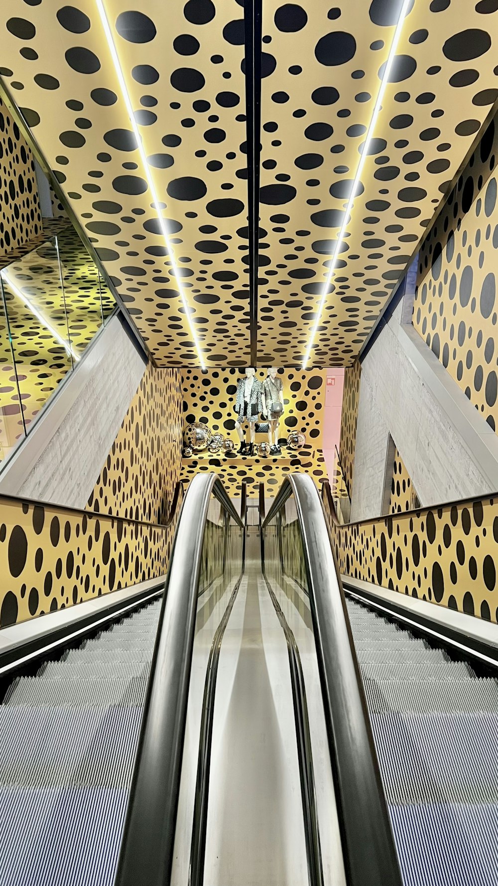 an escalator in a subway station with black and white dots on the ceiling