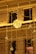 A warmly lit building facade with intricate decorative light fixtures, including a glowing orb surrounded by string lights and electric wires.