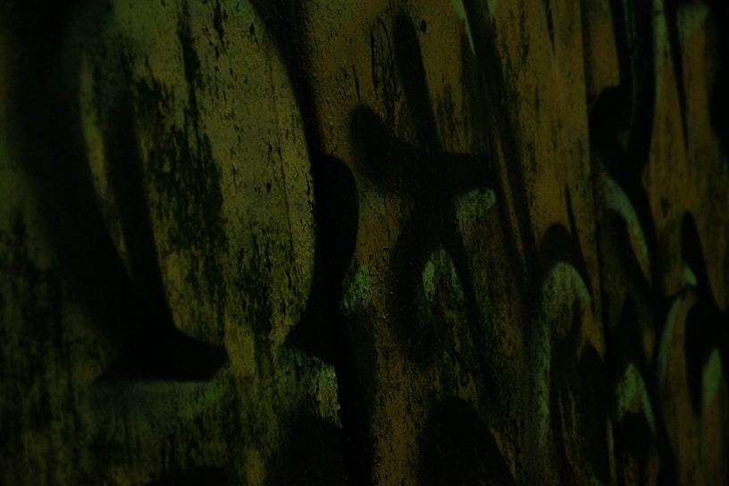 Dark urban mural with vivid red and blue graffiti elements under moody lighting.