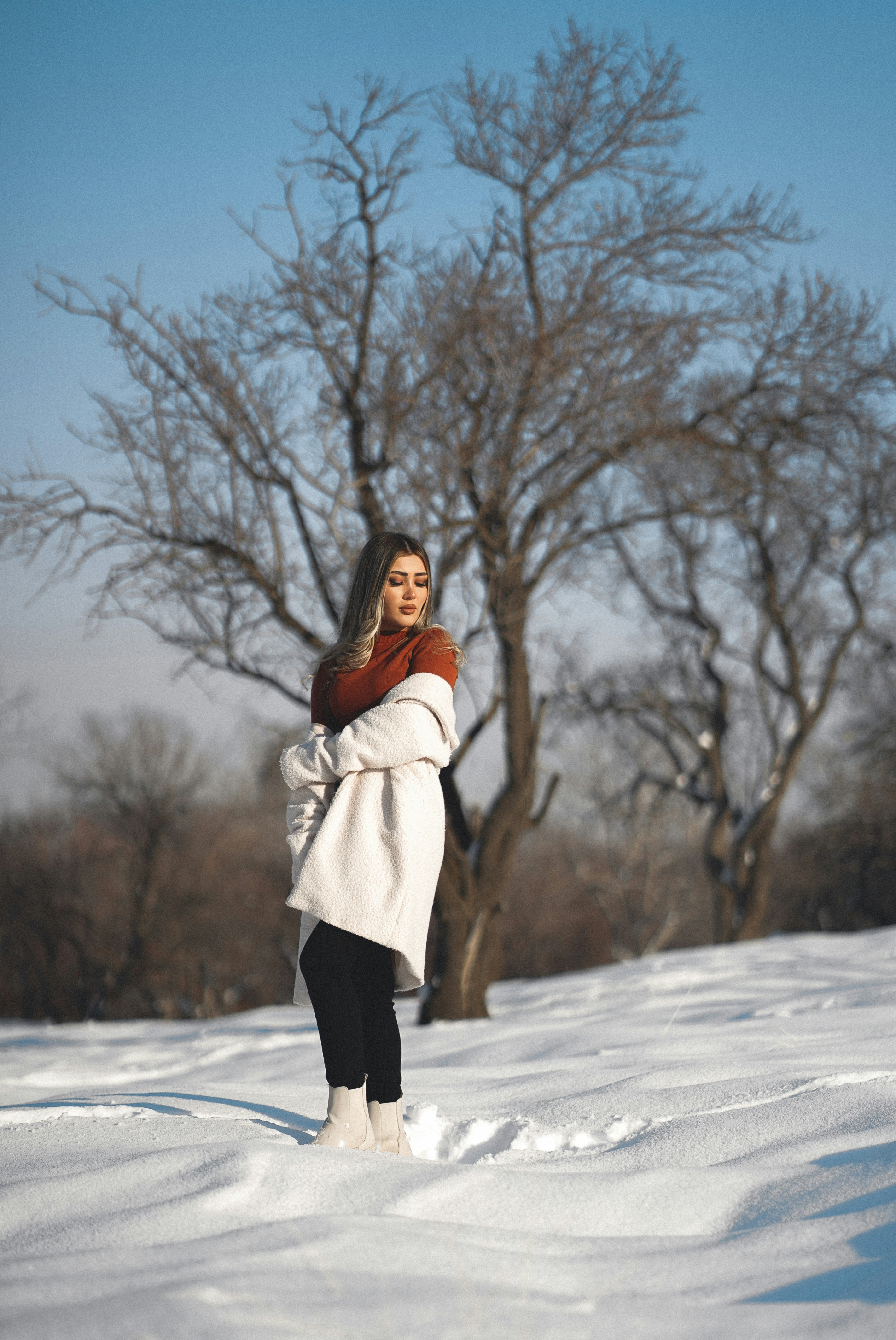 A woman standing in the snow in front of a tree photo – Free Art Image ...