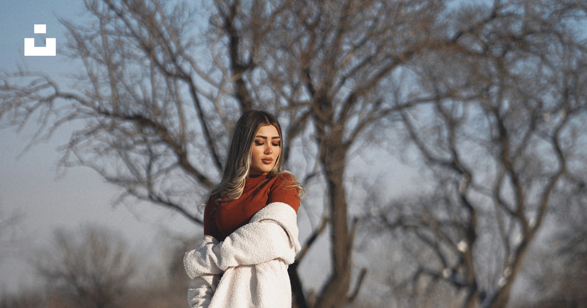 A woman standing in the snow in front of a tree photo – Free Art Image ...