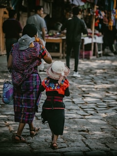 a woman and a child walking down a cobblestone street