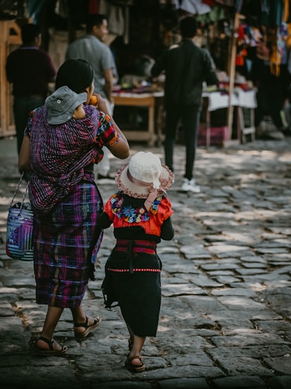 a woman and a child walking down a cobblestone street