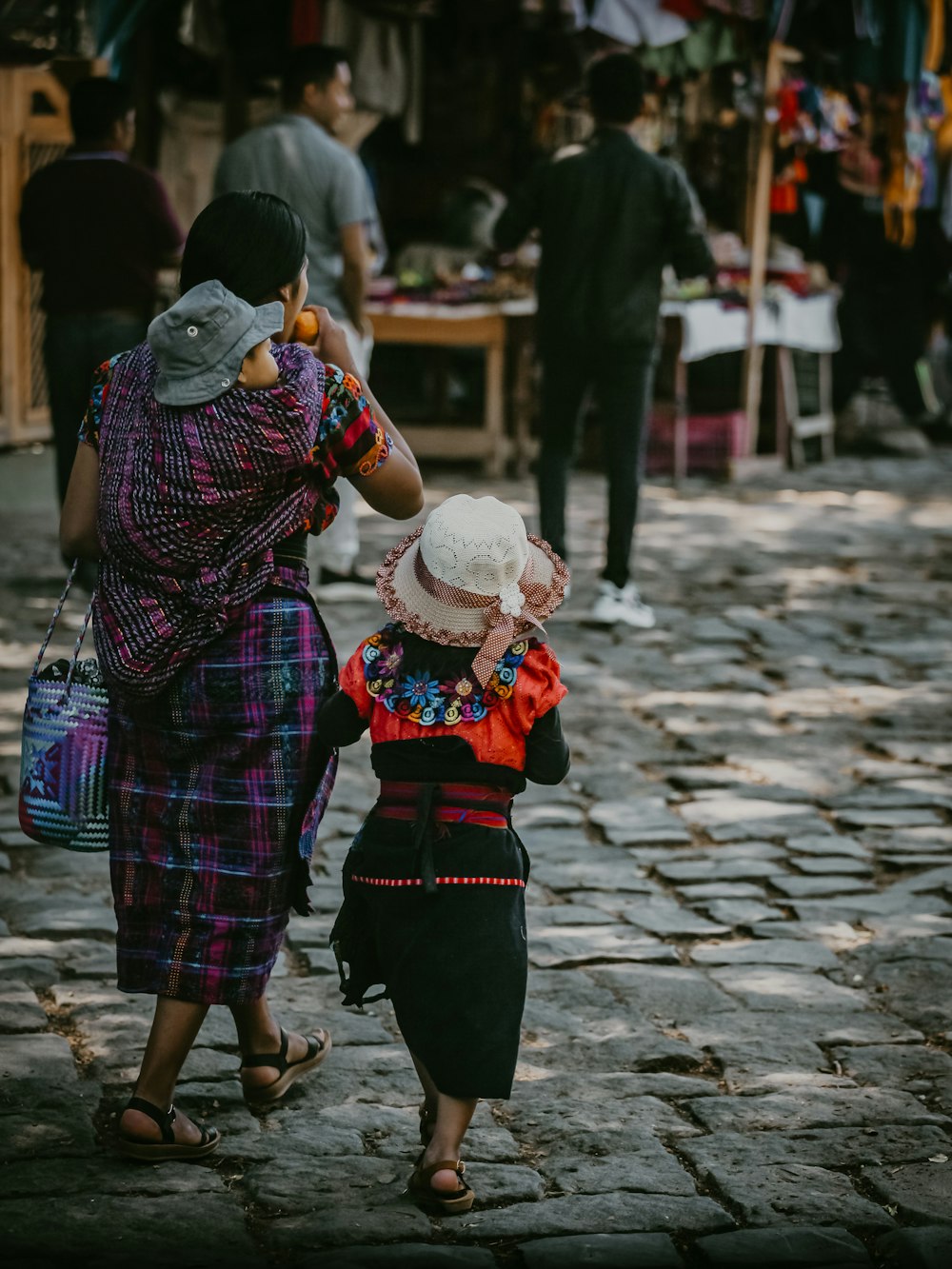 a woman and a child walking down a cobblestone street
