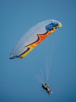 two people are parasailing in the blue sky