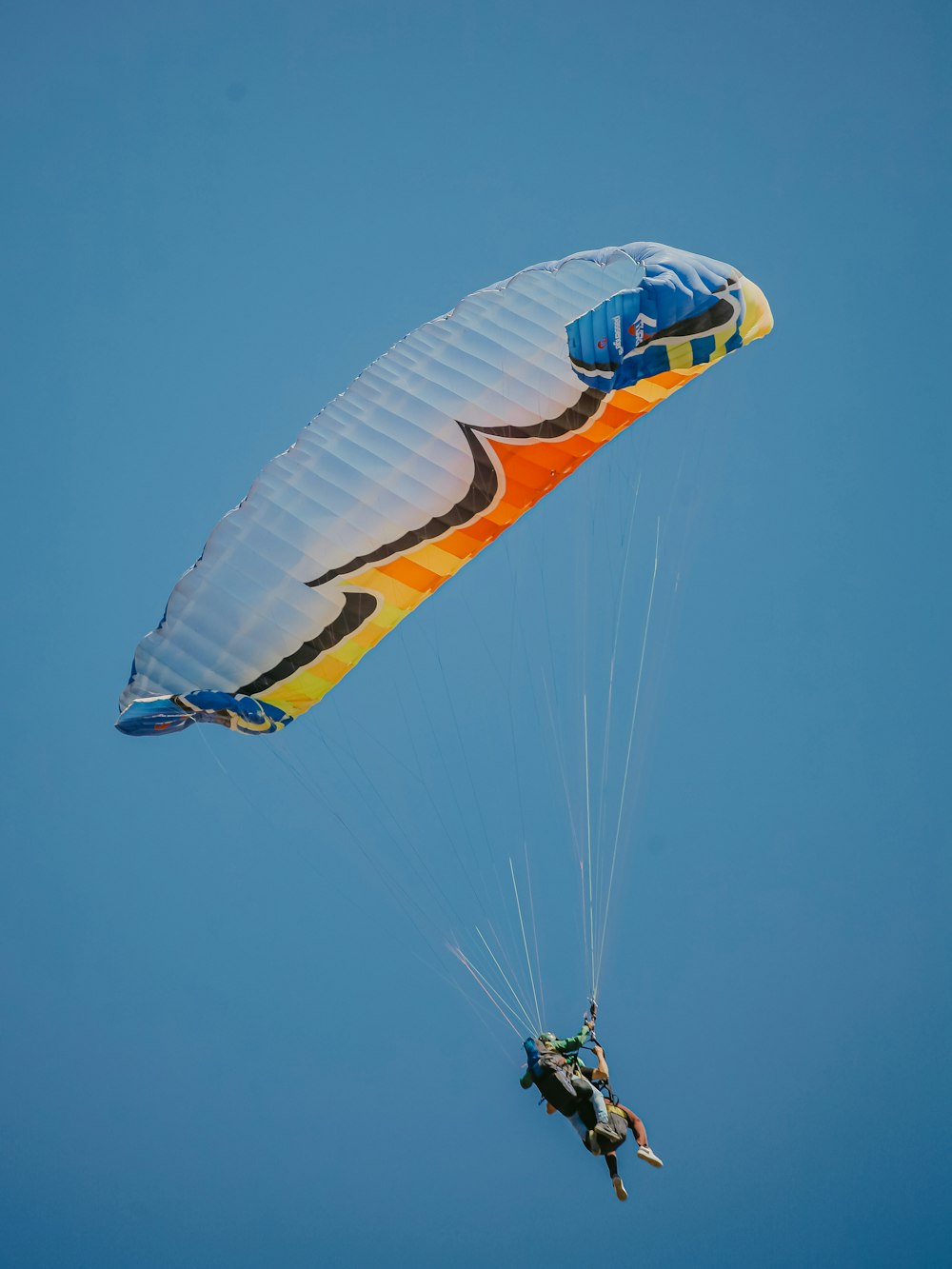 two people are parasailing in the blue sky