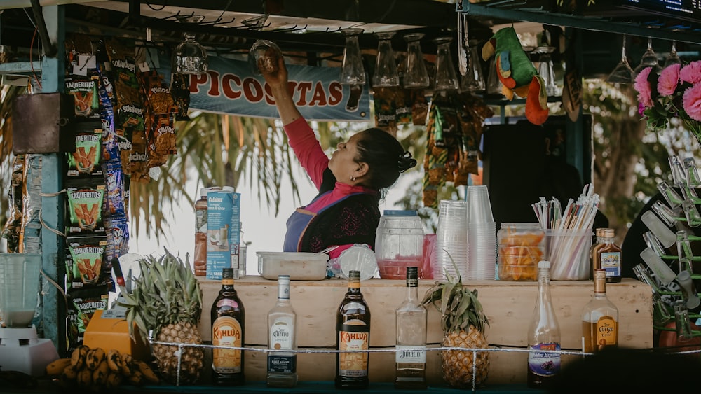 a woman standing behind a counter filled with drinks