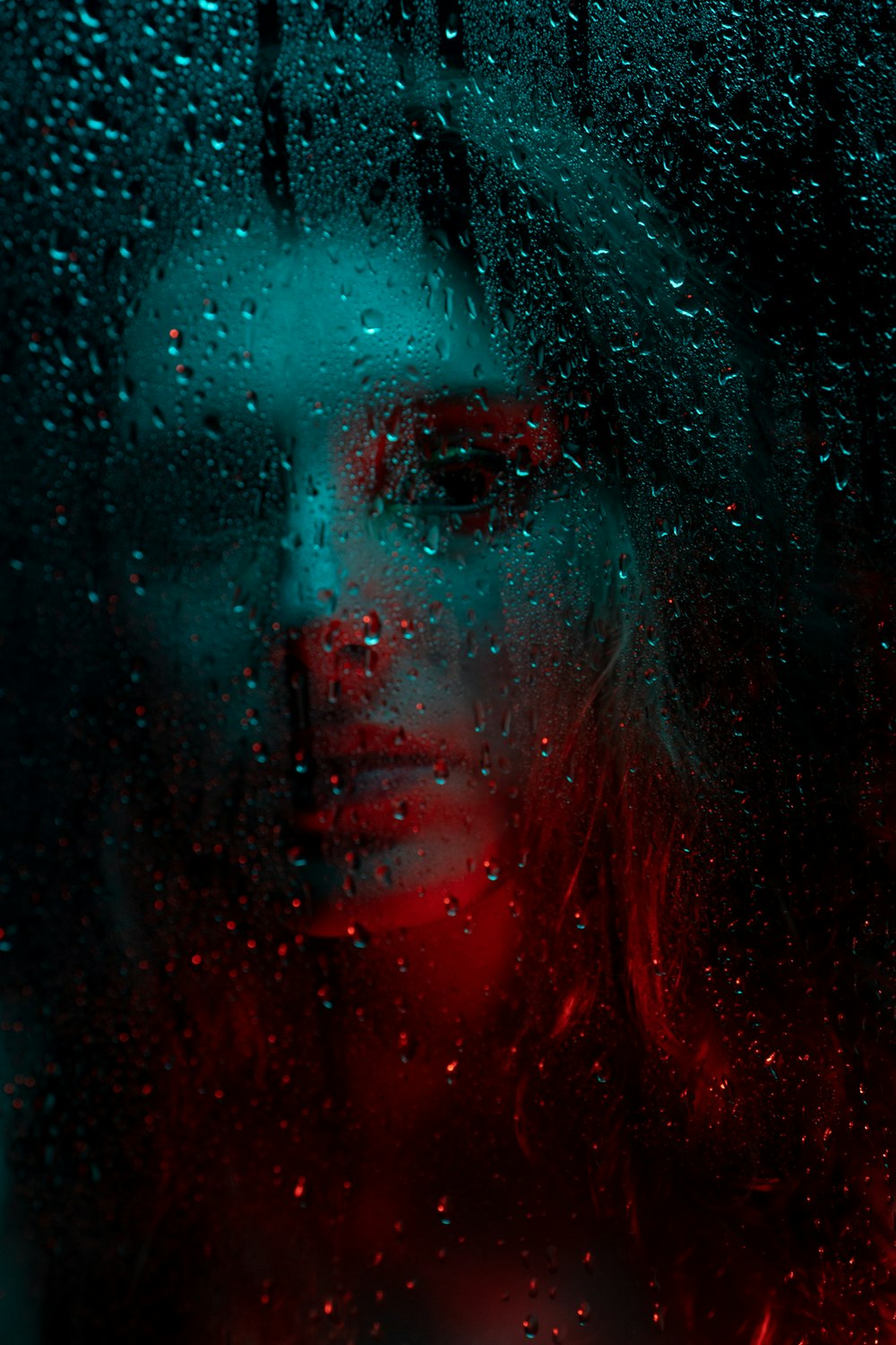 a woman is seen through a rain covered window