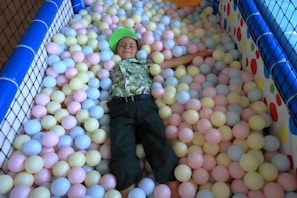 Kids laughing and playing in a bright ball pit under soft pastel lighting with stars and sparkles overhead