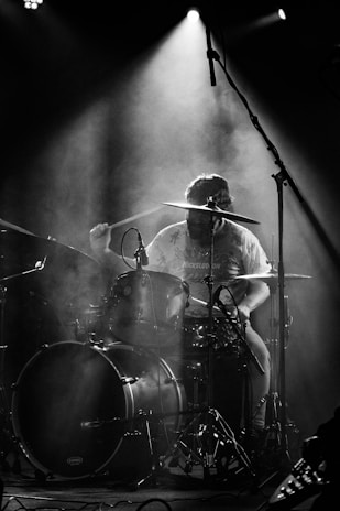 A drummer mid-beat, sweat flying, in the underground concert room.