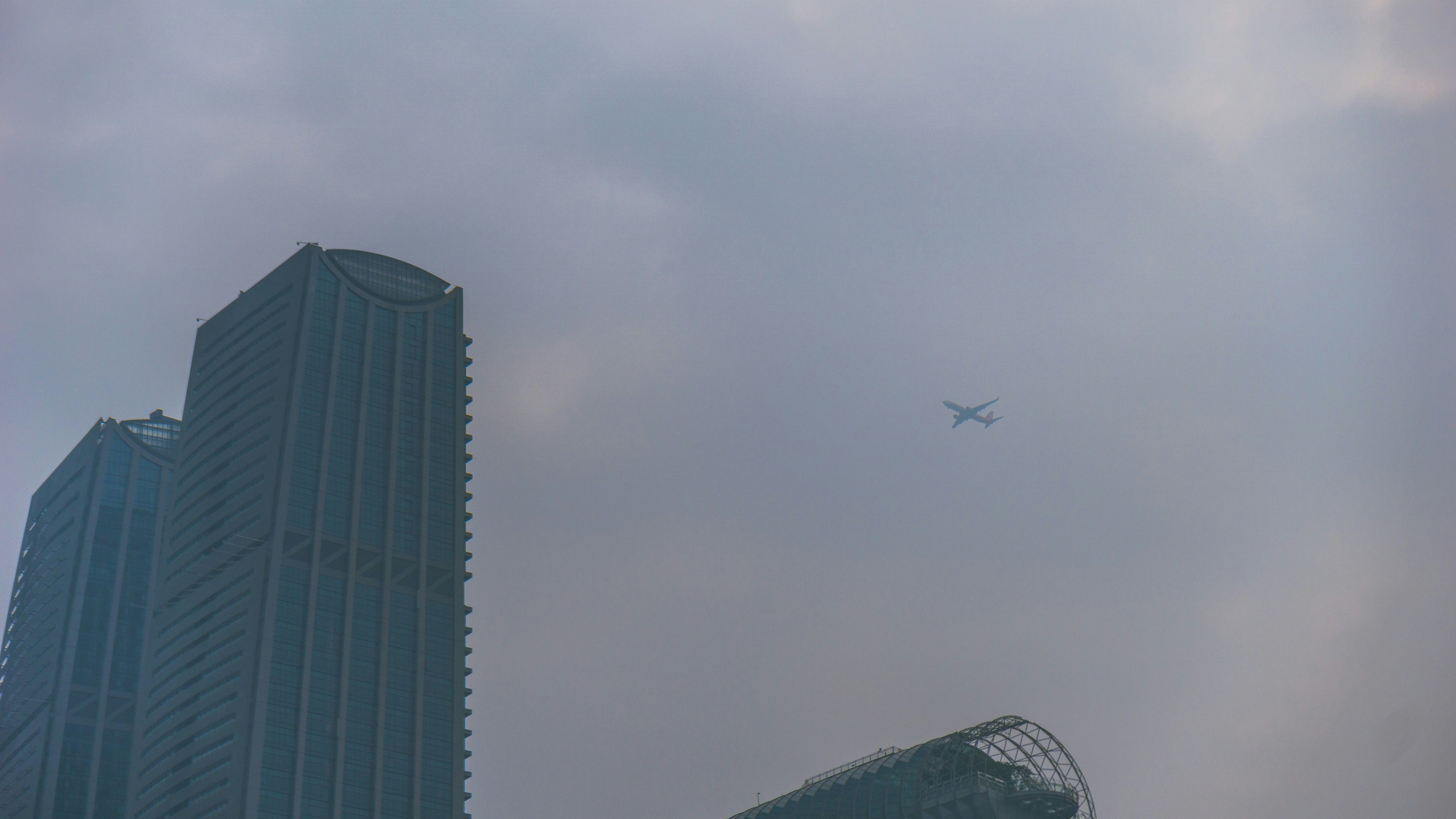 A plane flying over a tall building in the sky photo – Free China Image ...