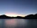 A serene image of a quiet lakeside at dusk with soft gray skies reflecting on the water.