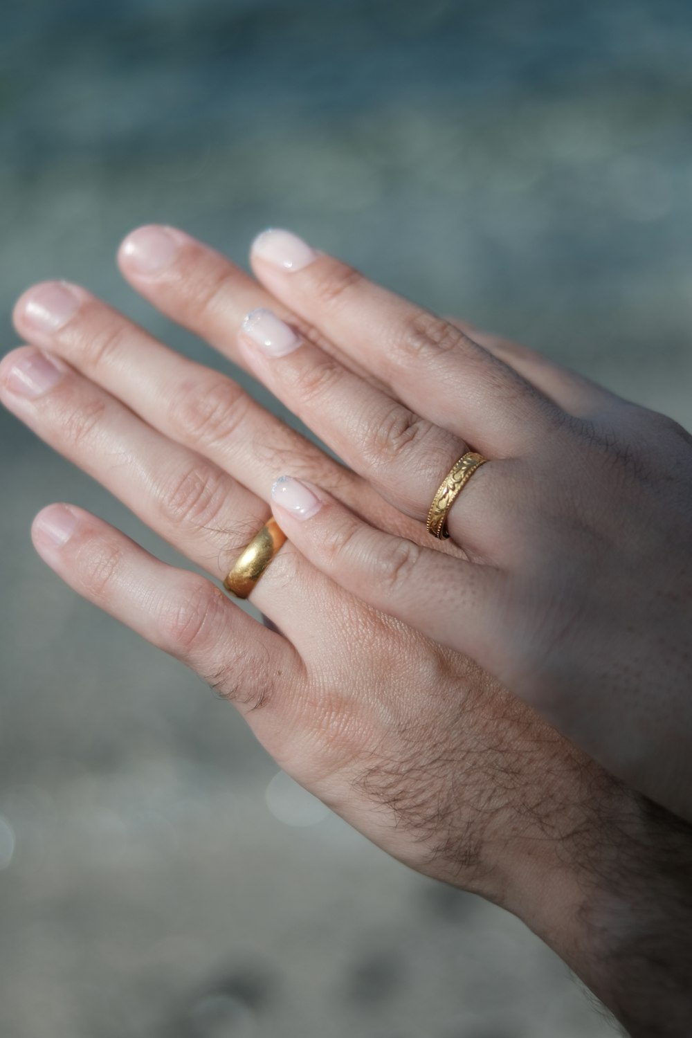 a person's hand with two gold rings on it