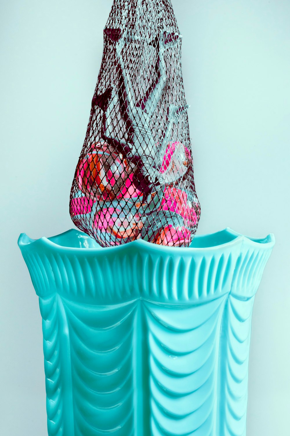 a mesh bag sitting on top of a blue vase