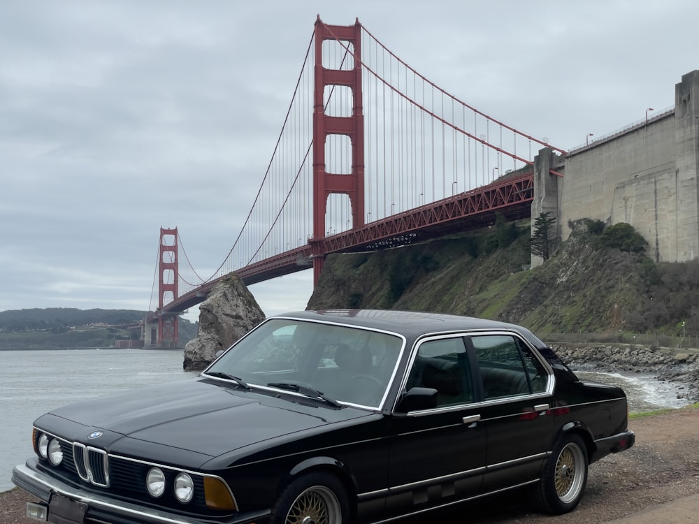 a black car parked in front of the golden gate bridge