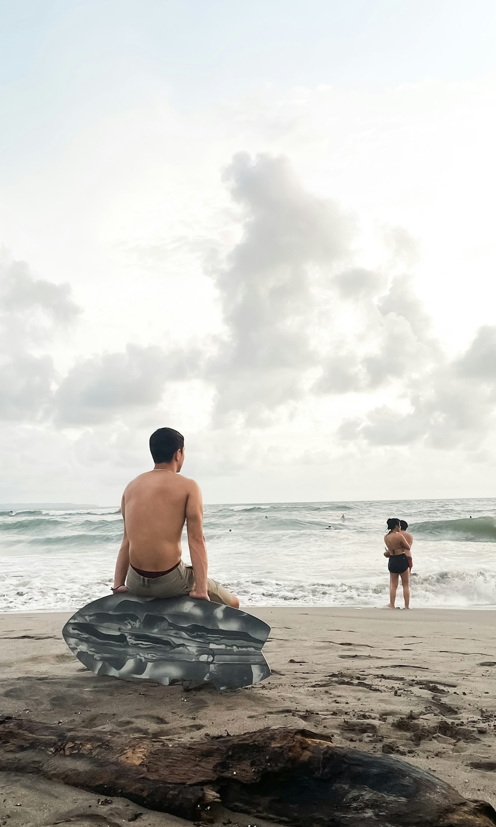 a man sitting on top of a rock near the ocean