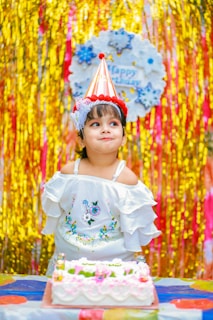 a little girl sitting in front of a birthday cake