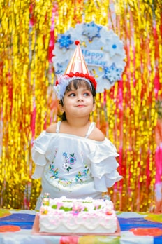 a little girl sitting in front of a birthday cake