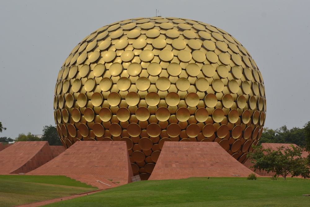 a large golden ball sitting on top of a lush green field