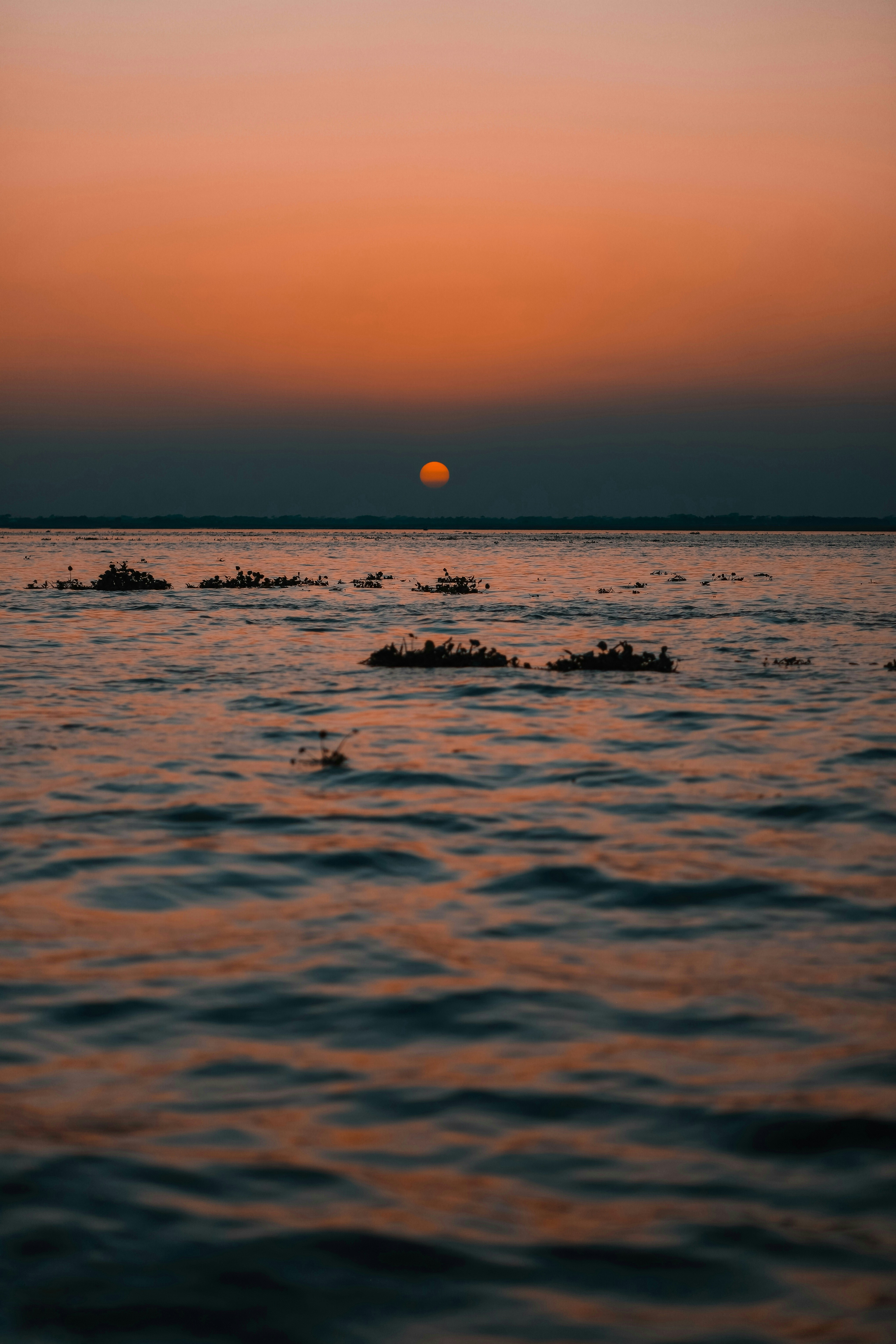 the sun is setting over the horizon of a body of water