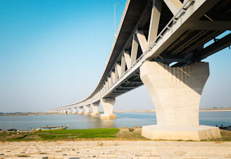 A wide-angle shot of a newly constructed government bridge over a river in West Bengal, showcasing sturdy pillars and smooth asphalt.