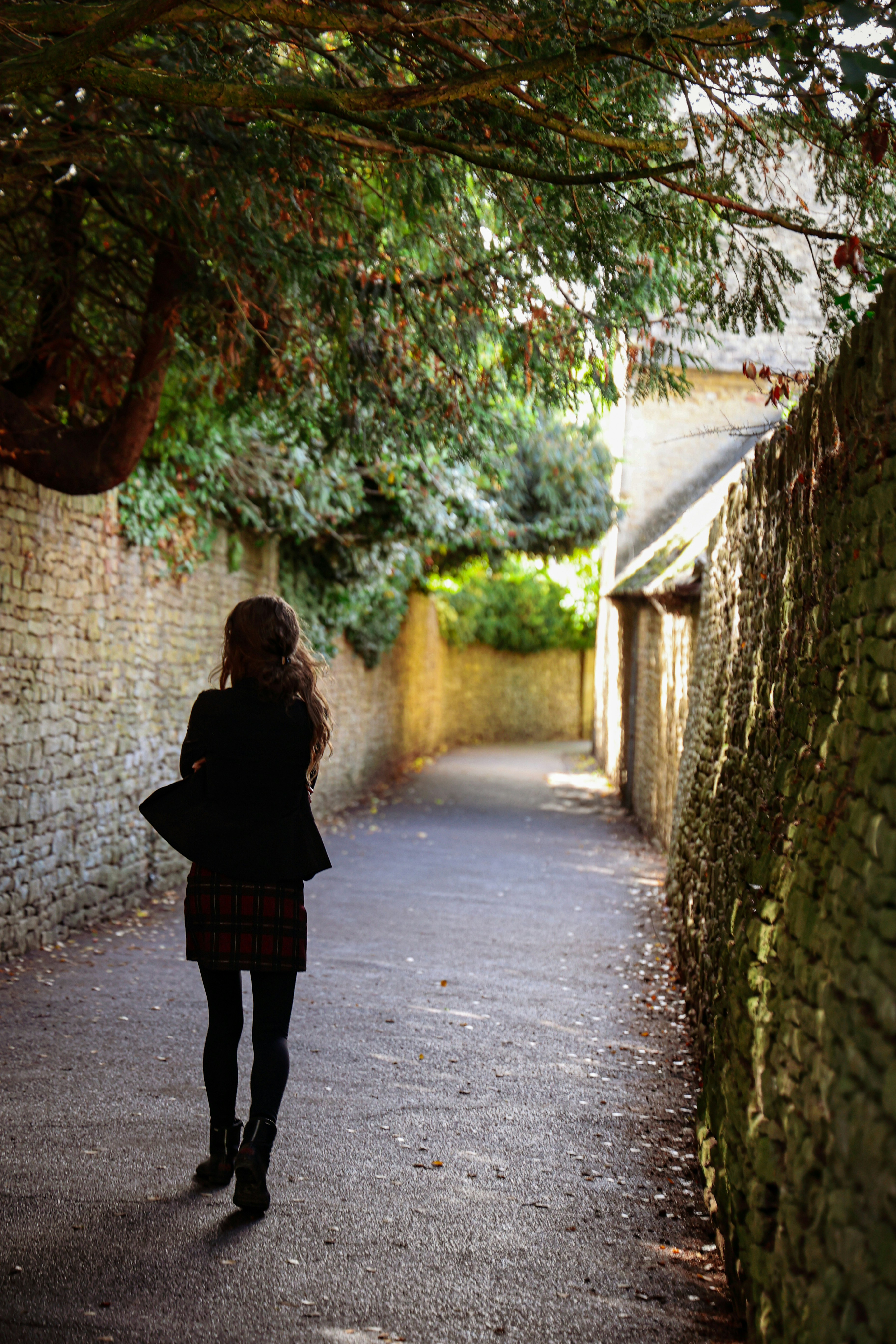 Una mujer caminando por una calle junto a un árbol