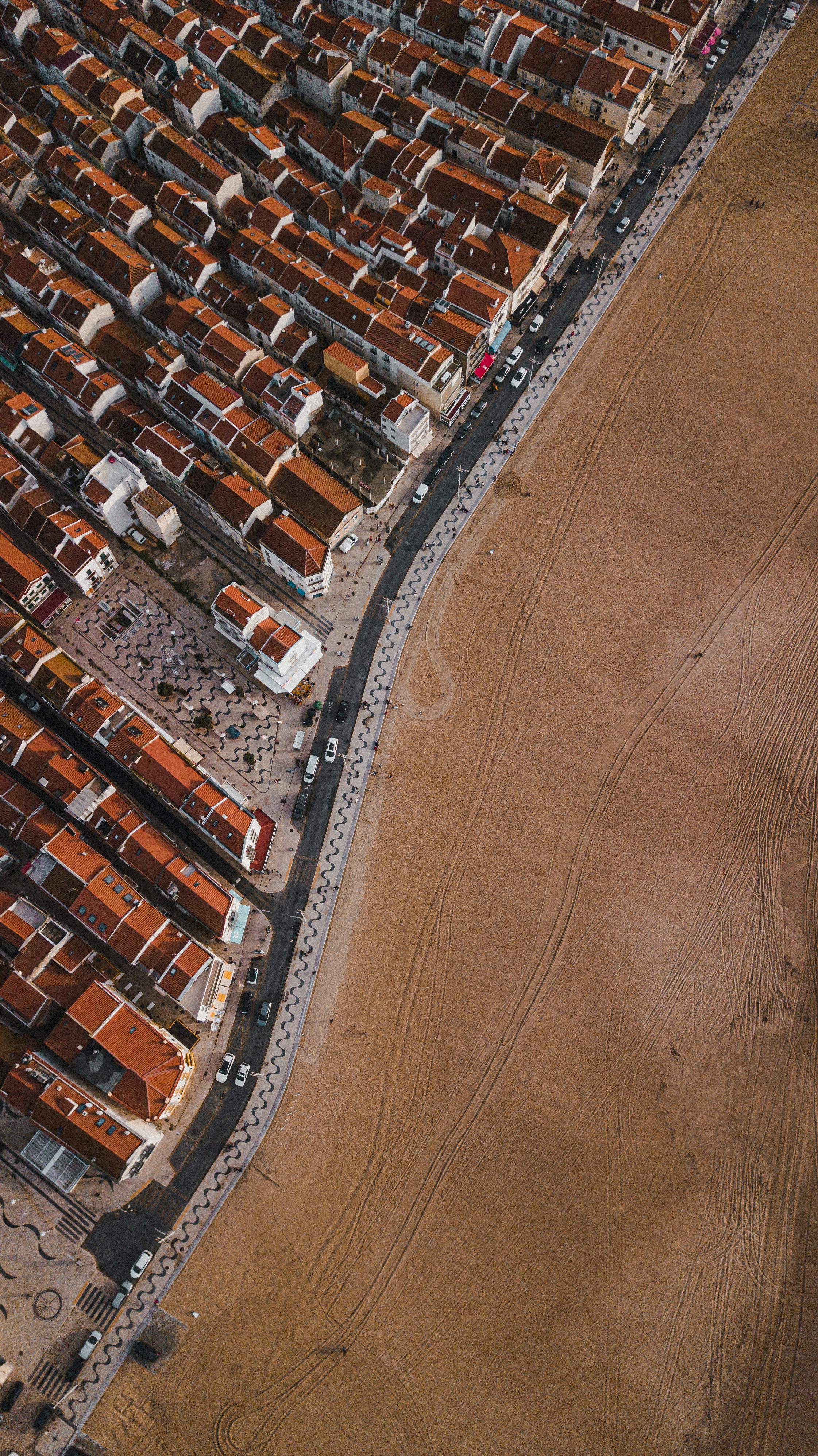 Aerial view of a beachside neighborhood with red roofs and sandy shore.