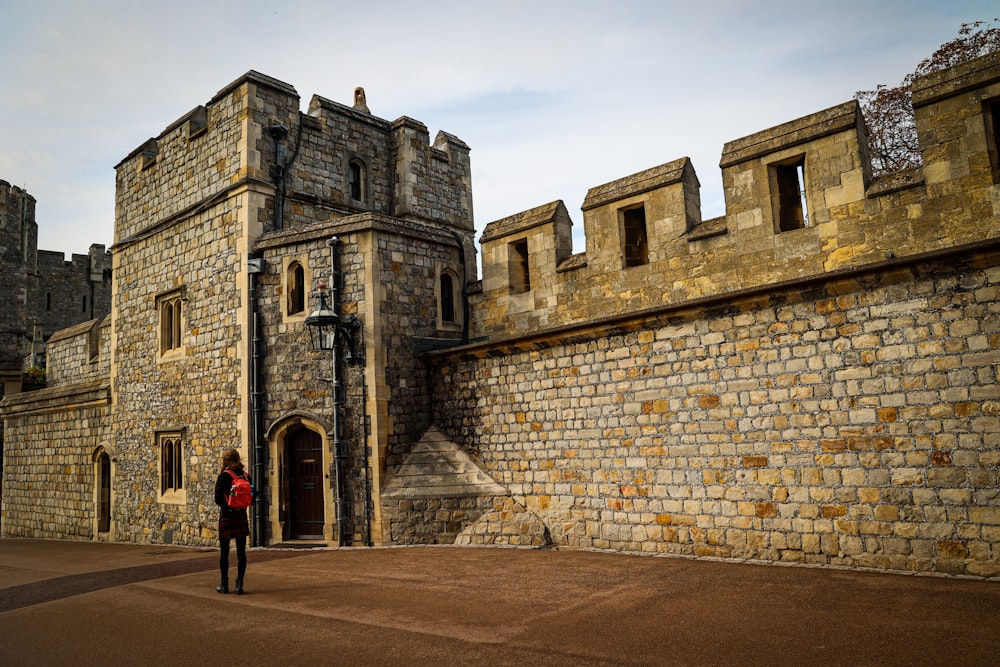 a woman standing in front of a stone castle